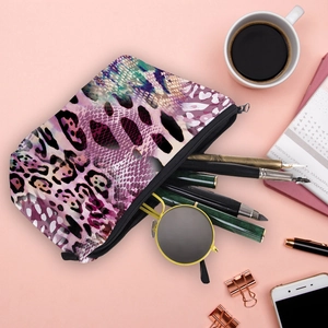 Stylish leopard print cosmetic bag with stationery and coffee on a pink background