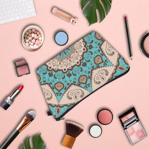 Flat lay of mandala pattern makeup bag with brushes and cosmetics on pink background