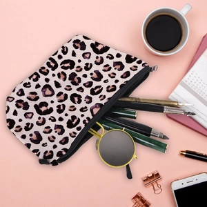 Leopard print makeup pouch for women with stationary and sunglasses on pink background