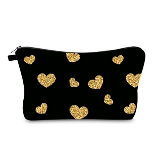 Detail of black fabric makeup bag featuring shiny gold sequin heart patterns and zipper