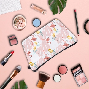 Flat lay of a bird print makeup bag surrounded by beauty products and cosmetic tools