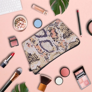 Toiletry bag with snake and leopard print patterns displayed with makeup accessories