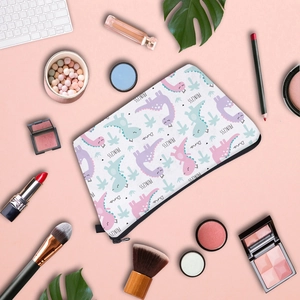 Flat lay of cute cartoon dinosaur makeup bag surrounded by cosmetics and accessories