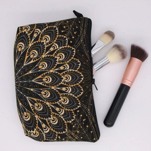 Detail view of a black mandala makeup bag with gold floral patterns and brushes