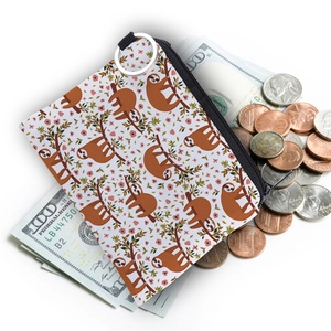 Water-resistant sloth print coin purse with metal keyring on top of dollar bills