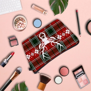 Flat lay of reindeer print plaid cosmetic bag with makeup brushes and perfume on pink background