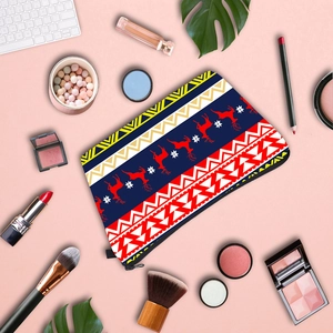 Flat lay of Fair Isle reindeer cosmetic bag with makeup brushes on pink background