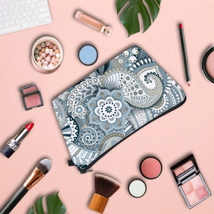 Water-resistant travel makeup bag with blue mandala pattern and zipper closure on pink background