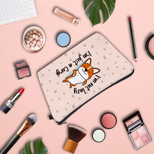 Flat lay of Corgi printed cosmetic bag with makeup accessories on pink background