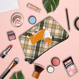 Flat lay of a Corgi printed plaid cosmetic bag with lipsticks and brushes on pink background