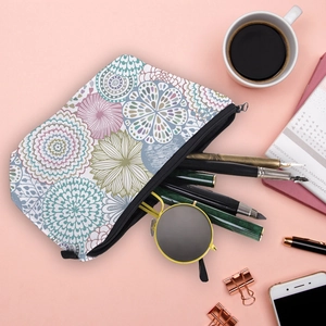 Flat lay of mandala print cosmetic bag with stationery and sunglasses on pink backdrop