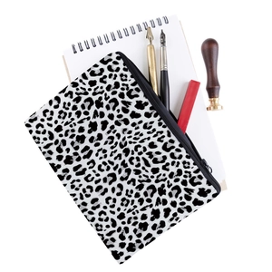 Leopard print makeup bag with black zipper shown with office stationery on white background