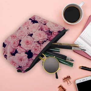 Water-resistant floral makeup bag with pink rose print and black zipper on a desk