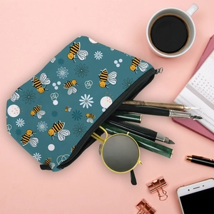Flat lay of water-resistant bee and daisy print makeup bag with pens and sunglasses