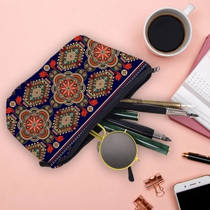 Mandala print makeup bag with ethnic patterns and black zipper on a pink desk surface