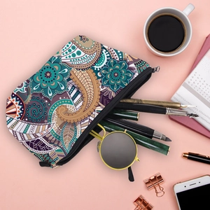 Flat lay of mandala paisley makeup bag holding sunglasses and stationery on a pink desk