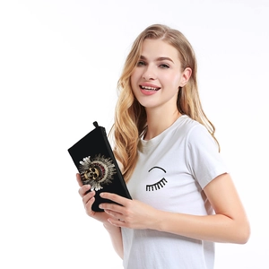 Detail of skull print makeup bag with gold headdress held by model on white backdrop