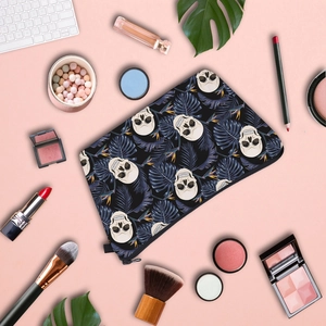 Skull and tropical leaf printed makeup bag with beauty accessories on pink background