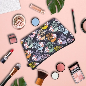Flat lay of skull and floral print cosmetic bag with makeup brushes on pink background
