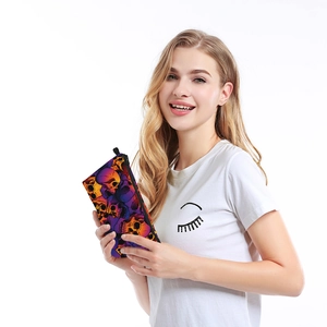 Fashionable skull print makeup bag with waterproof zipper and side strap held by hand