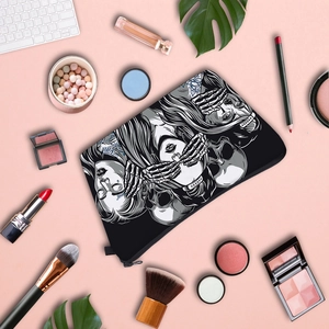 Flat lay of a skull print makeup bag with cosmetics on a soft pink background