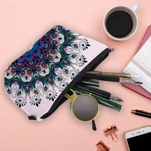 Flat lay of mandala print makeup bag holding sunglasses and pens on a pink desk