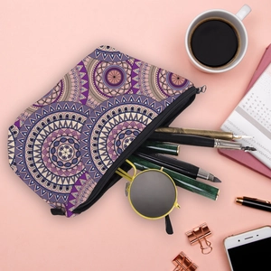 Flat lay of mandala printed travel makeup bag with sunglasses and pens on pink background