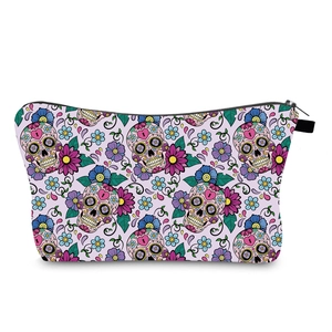 Gros plan sur l'imprimé tête de mort et fleurs d'une trousse de maquillage de voyage mauve
