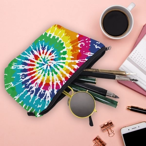 Waterproof rainbow tie-dye makeup bag with zipper closure shown in a flat lay desktop scene