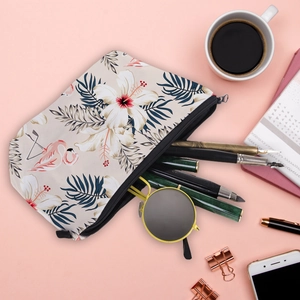 Waterproof toiletry bag with flamingo and hibiscus print on a pink desk background