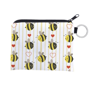 Close-up of small fabric coin purse with bee print, black zipper, and silver key ring