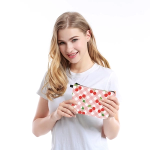 Waterproof travel cosmetic bag with cherry print and pink checkered pattern held by a model