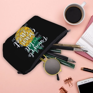 Waterproof black pineapple print makeup bag for travel storage on pink desk setup