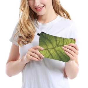 Green leaf print makeup bag for travel held by a model with realistic leaf texture