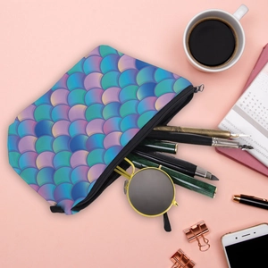 Flat lay of mermaid scale makeup bag containing pens and round sunglasses