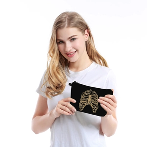 Portable black makeup bag with golden rib skeleton print shown by a female model