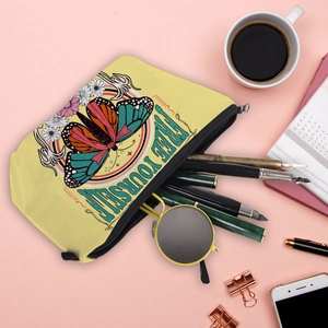 Flat lay of yellow canvas butterfly makeup bag with Free Yourself text on pink desk