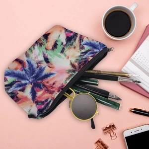 Flat lay of tropical palm leaf makeup bag with zipper, sunglasses, and stationery