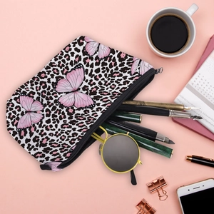 Flat lay of pink butterfly leopard makeup bag with sunglasses and office supplies