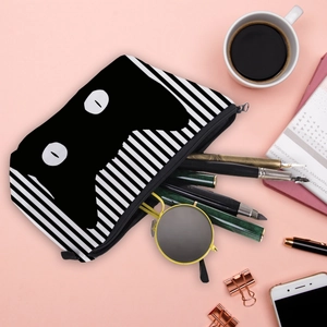 Flat lay of striped black cat makeup bag storing stationery and sunglasses on pink background