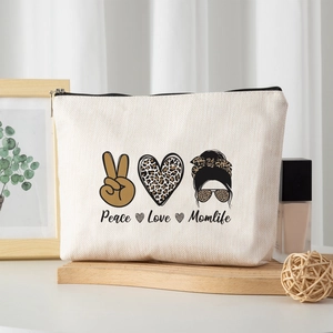 Faux linen makeup bag with Peace Love Momlife print and black zipper on wooden base