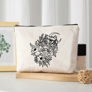 Linen-look cosmetic bag with owl and moon art on wood tray with stylish props