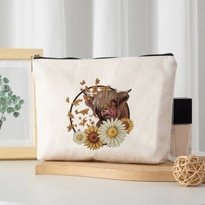 Linen makeup bag with Highland cow and sunflower print on a wooden display shelf