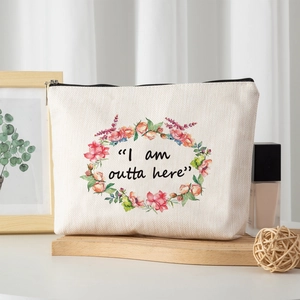 Detail of floral linen makeup bag with I am outta here print on a wooden tray
