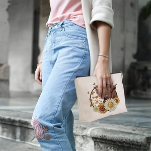 Outdoor model holding linen makeup bag with highland cow and sunflower floral print