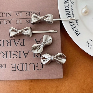 French metallic silver bow hair clip and stud earrings on vintage book and tray
