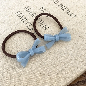 Par de gomas para el pelo hechas a mano con lazo de acetato azul sobre fondo beige