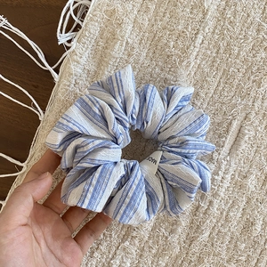 Gros plan détaillé d'un chouchou en tissu à rayures bleues et blanches avec étiquette