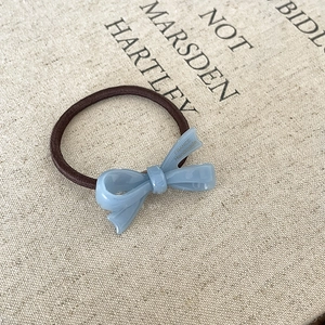 Detalle de coletero con lazo azul de acetato y letras doradas de fabricación artesanal