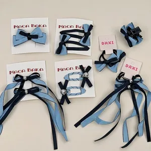 Lot de barrettes à nœuds bleu et noir avec rubans et détails métalliques sur carte